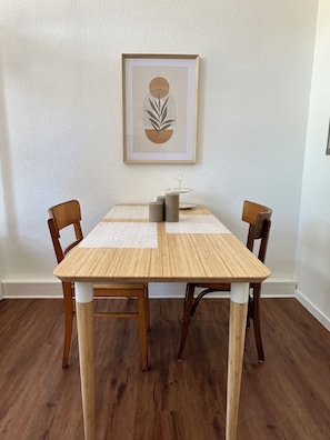 A dining table with chairs, a framed artwork on the wall, and a small decorative item on the table. - Sechser in Münster Roxel—10 minutes from the UKM (Münster)