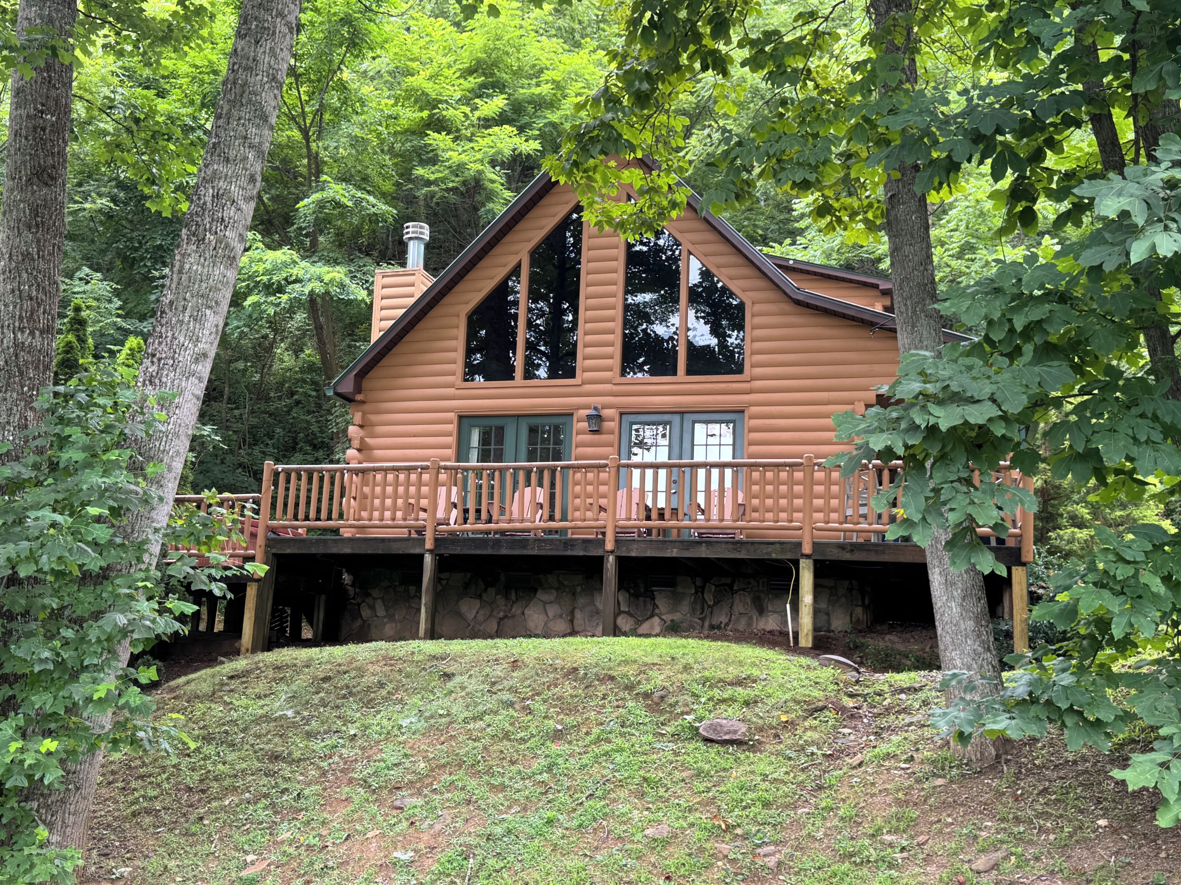 A log cabin with a balcony, surrounded by trees.
