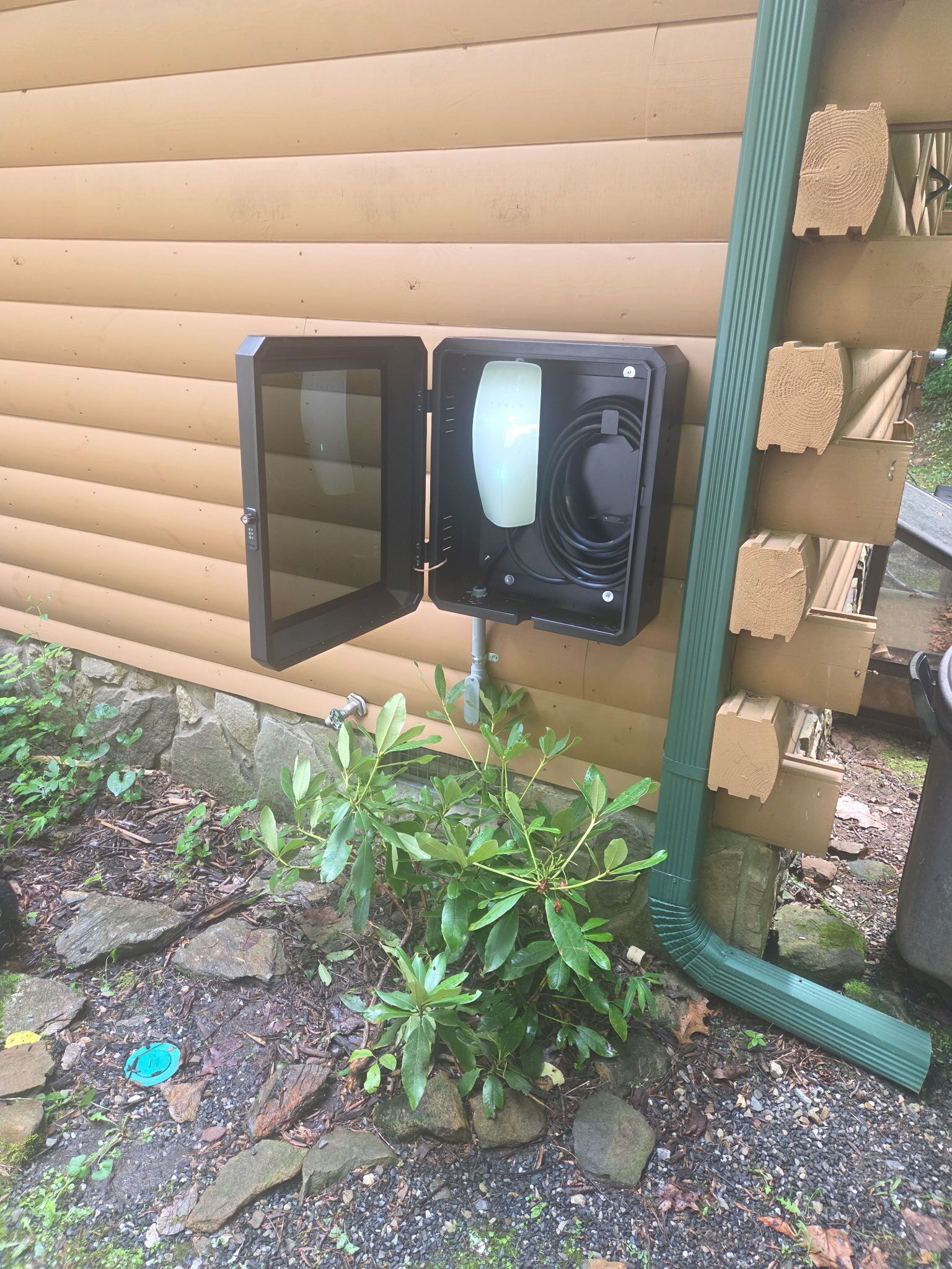 Une prise de courant fixée au mur, avec un tuyau vert à proximité.
