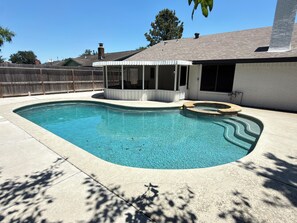 A swimming pool with a built-in hot tub, a covered patio area, and a fenced backyard. - Private 3BR Pool Retreat Near Houston (Deer Park)