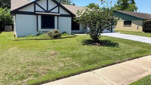 A single-story house with a gabled roof, a front yard with a small tree, and a clear sky. - Private 3BR Pool Retreat Near Houston (Deer Park)