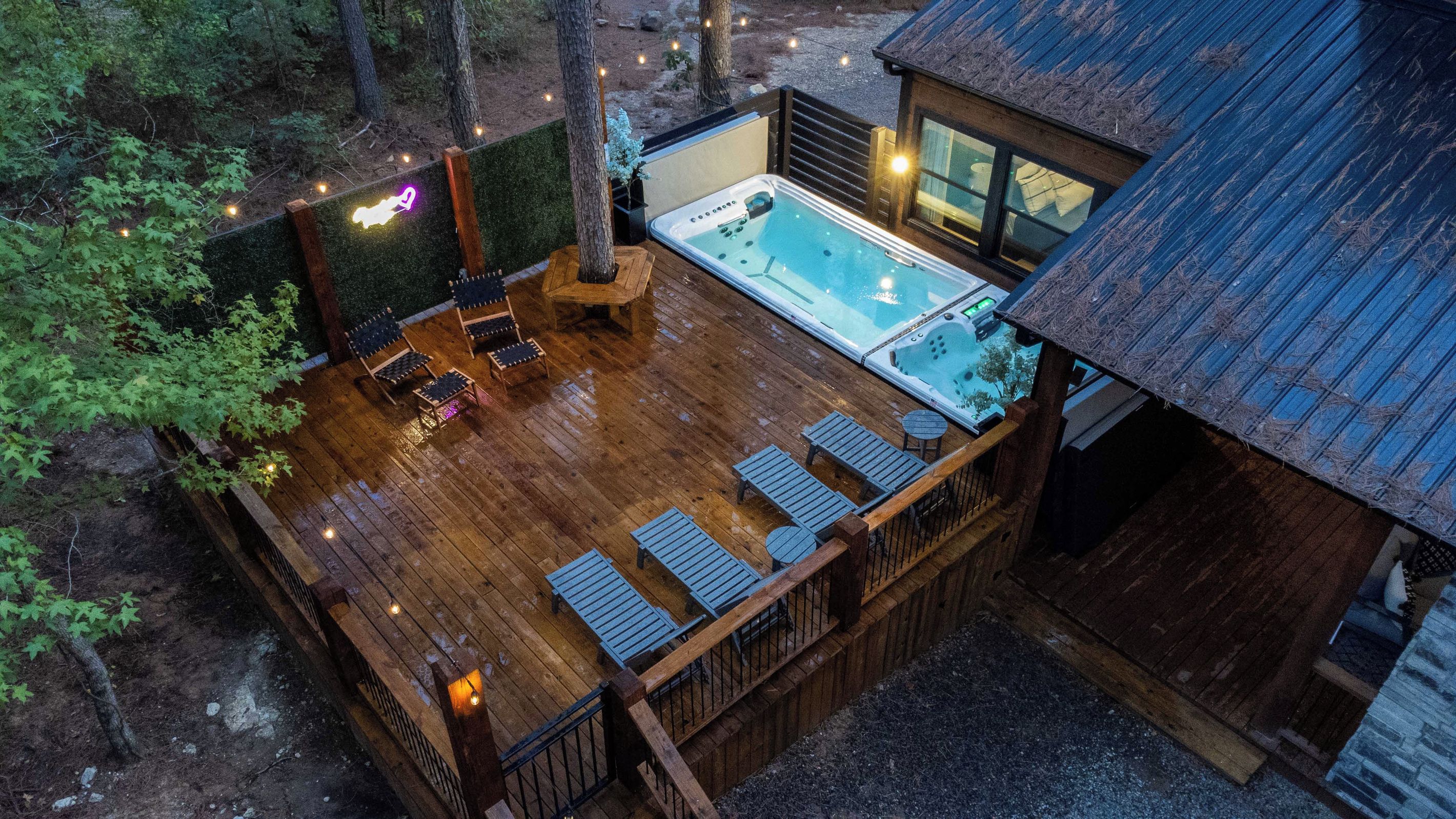 Terraza de madera con un jacuzzi, sillones de descanso y una pequeña mesa.
