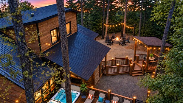 A wooden deck with lounge chairs and a hot tub, surrounded by trees. - 21-Ft Swim Spa Pool | 2 King Suites | Game Loft | Playset | Swings | Hot tub (Broken Bow)