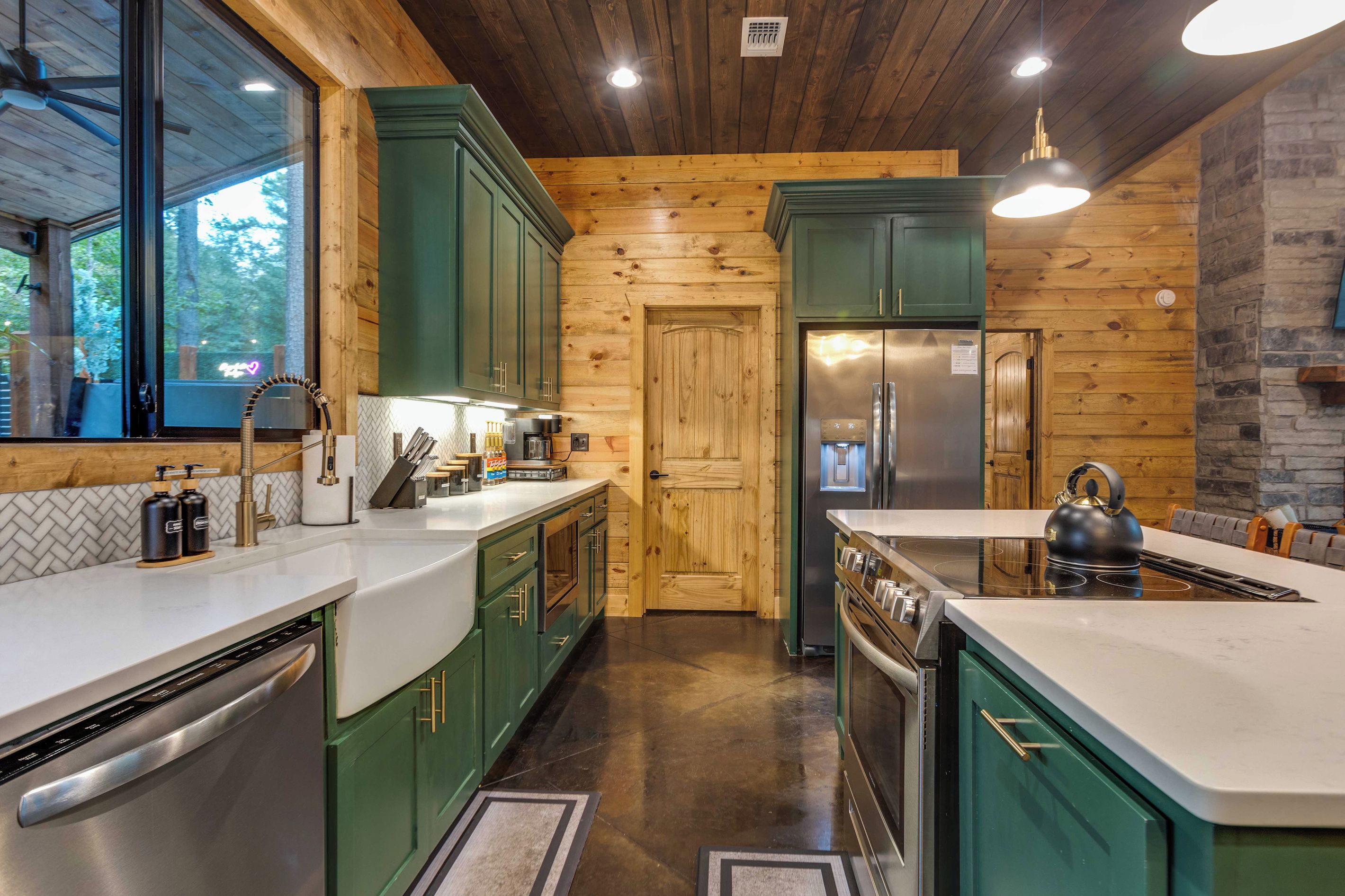 Una cocina moderna con armarios verdes, electrodomésticos de acero inoxidable y techo de madera.