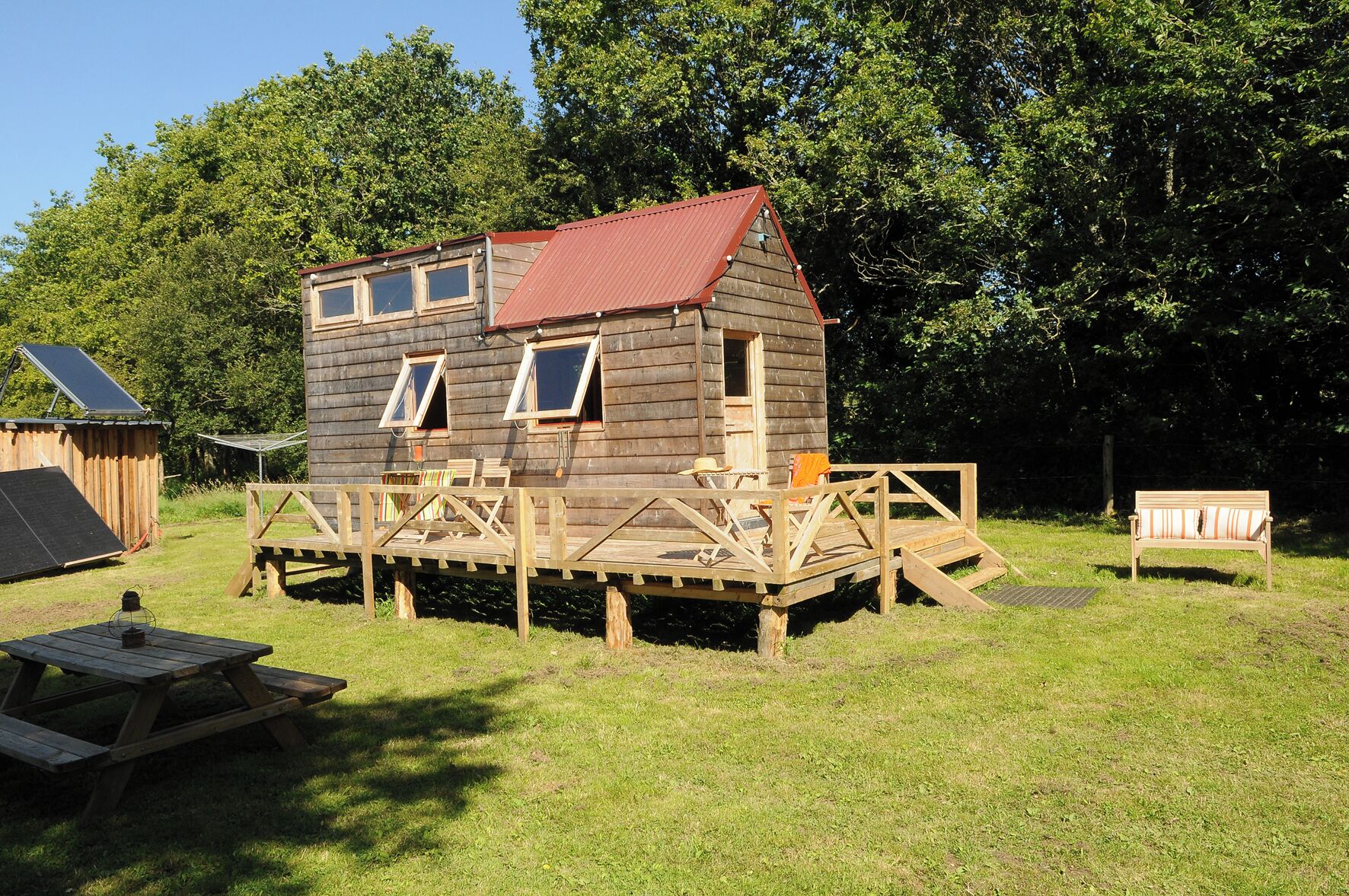 Eine Holzhütte mit einer Veranda, einem Picknicktisch und einer Bank.