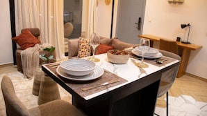 A dining area with a table set for two, a sofa, and a small side table with a lamp. - LE DANORE VIP APPART hotel (Yaoundé)