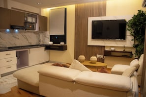 Una sala de estar moderna con un sofá, un televisor, una mesita y una planta.