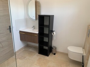 A bathroom with a white sink, a black shelf, a toilet, and a mirror. - 65-square-meter house, fully air-conditioned, with a spa (Bormes-les-Mimosas)