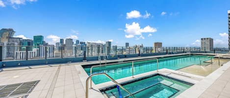 A rooftop pool with clear blue water, surrounded by a city skyline view.