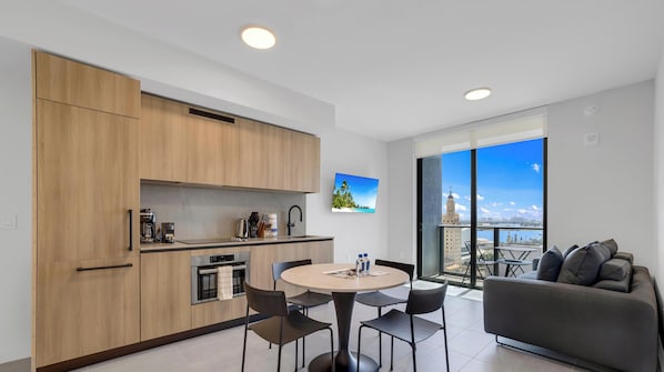 Una cocina moderna con comedor, sofá y un amplio ventanal con vistas a la ciudad.