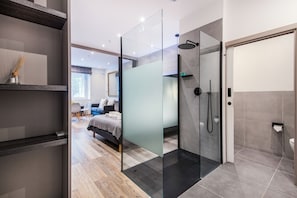 A modern bathroom with a glass shower enclosure, a toilet, and a sink. - SomersetHouseSuites by Aureva Residences (London)