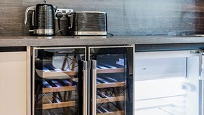 Una cocina moderna con horno integrado, cafetera y refrigerador pequeño.