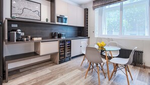 Una cocina moderna con electrodomésticos integrados, un comedor con mesa y sillas, y un amplio ventanal que proporciona luz natural.