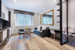 A modern living room with a dining area, a sofa, and a large mirror. - SomersetHouseSuites by Aureva Residences (London)