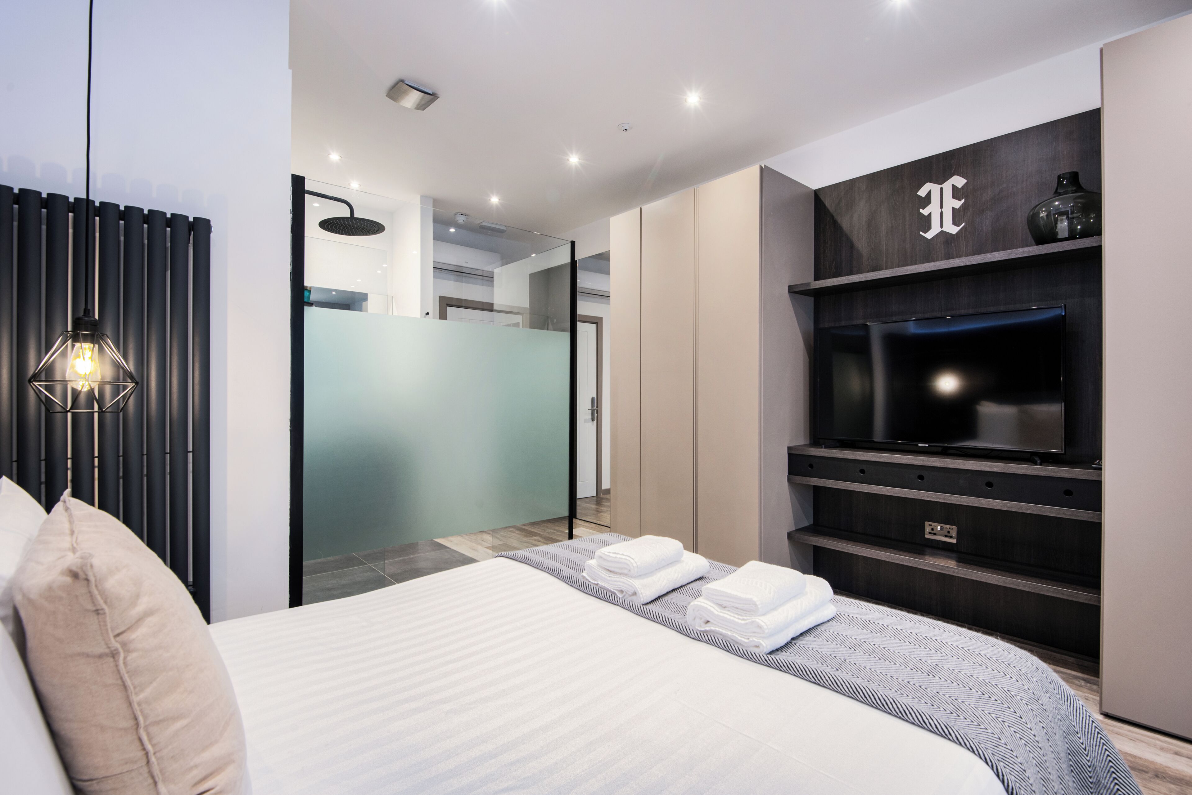 Een moderne hotelkamer met een bed, een televisie, een badkamer en een douche.