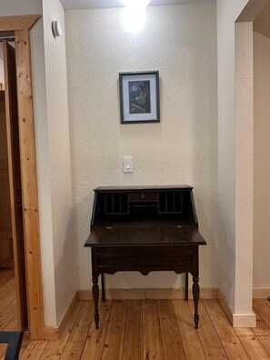 A dark wooden desk with drawers, a framed picture on the wall, and a light switch. - Spacious, Private Suttons Bay Oasis in the Woods (Suttons Bay)