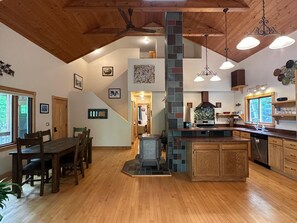 A spacious kitchen with a central island, wooden ceiling, and a stone accent wall.