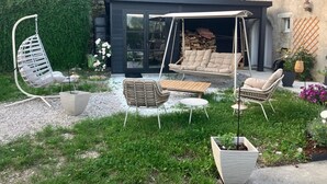 Ein moderner Außenbereich mit einer Schaukelstuhlsitzgruppe, einer gepolsterten Couch und einem Holztisch.