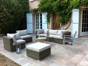 An outdoor seating area with wicker furniture and a round table. - A haven of peace in a protected natural area. (Le Luc)