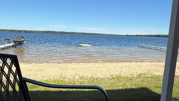 A lakeside view with a dock, a boat, and a grassy area.