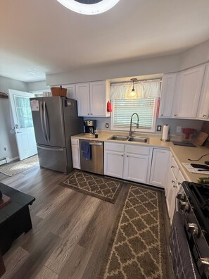 A modern kitchen with white cabinets, stainless steel appliances, a built-in oven, and a gas stove.