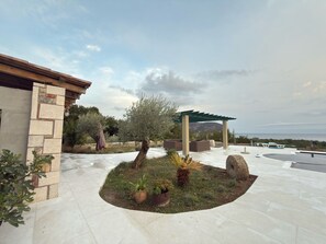 A patio area with a pergola, seating, and potted plants.