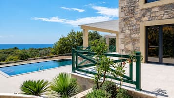 Une piscine avec un mur en pierre et vue sur la mer.