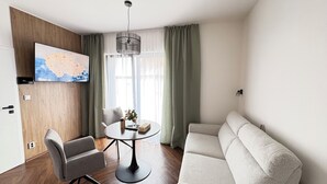 Un saló modern amb un sofà, una taula de dinar amb cadires, un televisor fixat a la paret i un mapa.