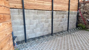 Un pati amb un paviment de rajoles de disseny, una tanca de fusta i una paret de pedra.