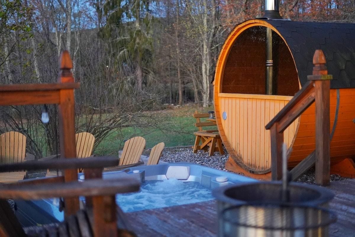 Un bain à remous entouré d’une terrasse, avec des chaises et une table en bois.
