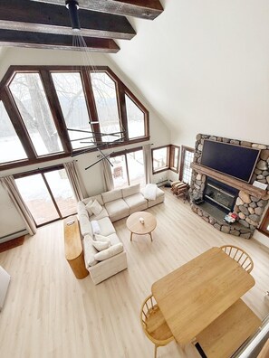 Un salón espacioso con chimenea de piedra, un televisor grande y una mesa de comedor de madera.