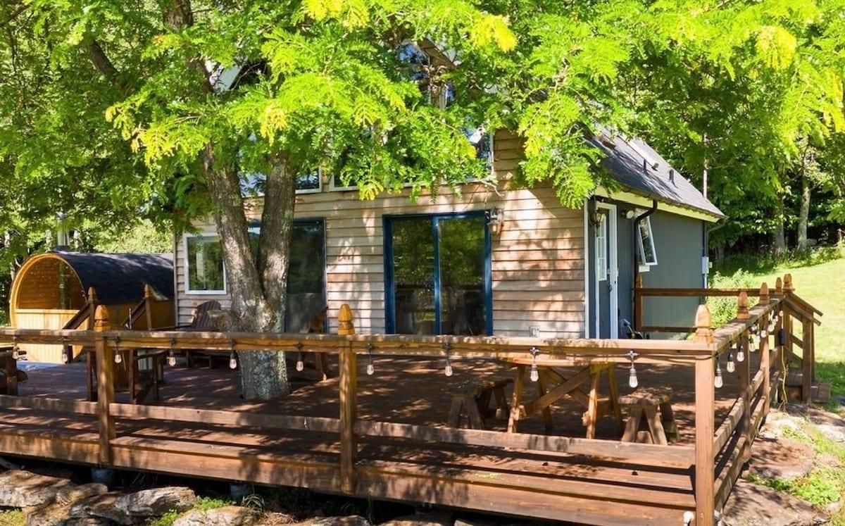 A cabin with a wooden deck, a covered area, and a small porch.