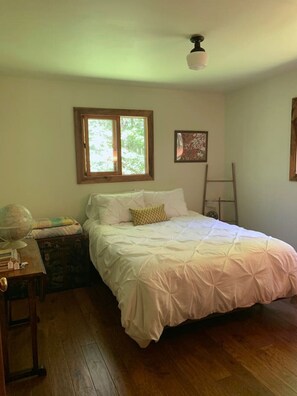 Ein Schlafzimmer mit Bett, Schreibtisch mit Globus, Fenster und einer Leiter.
