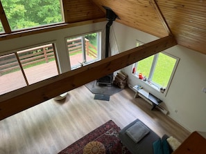 Ein Zimmer mit hohen Decken, einem großen Fenster, einem Kamin und Blick auf eine Terrasse.