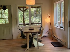 Ein Essbereich mit Tisch und Stühlen, einer Stehlampe und Blick durch ein Fenster.