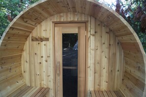 A wooden cabin with a circular roof, a door, and a bench inside. - Ash, the tiny cabin in the woods (Markdale)