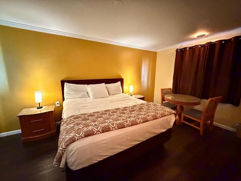 Une chambre d’hôtel avec un lit, des tables de chevet, une chaise et une fenêtre avec des rideaux.