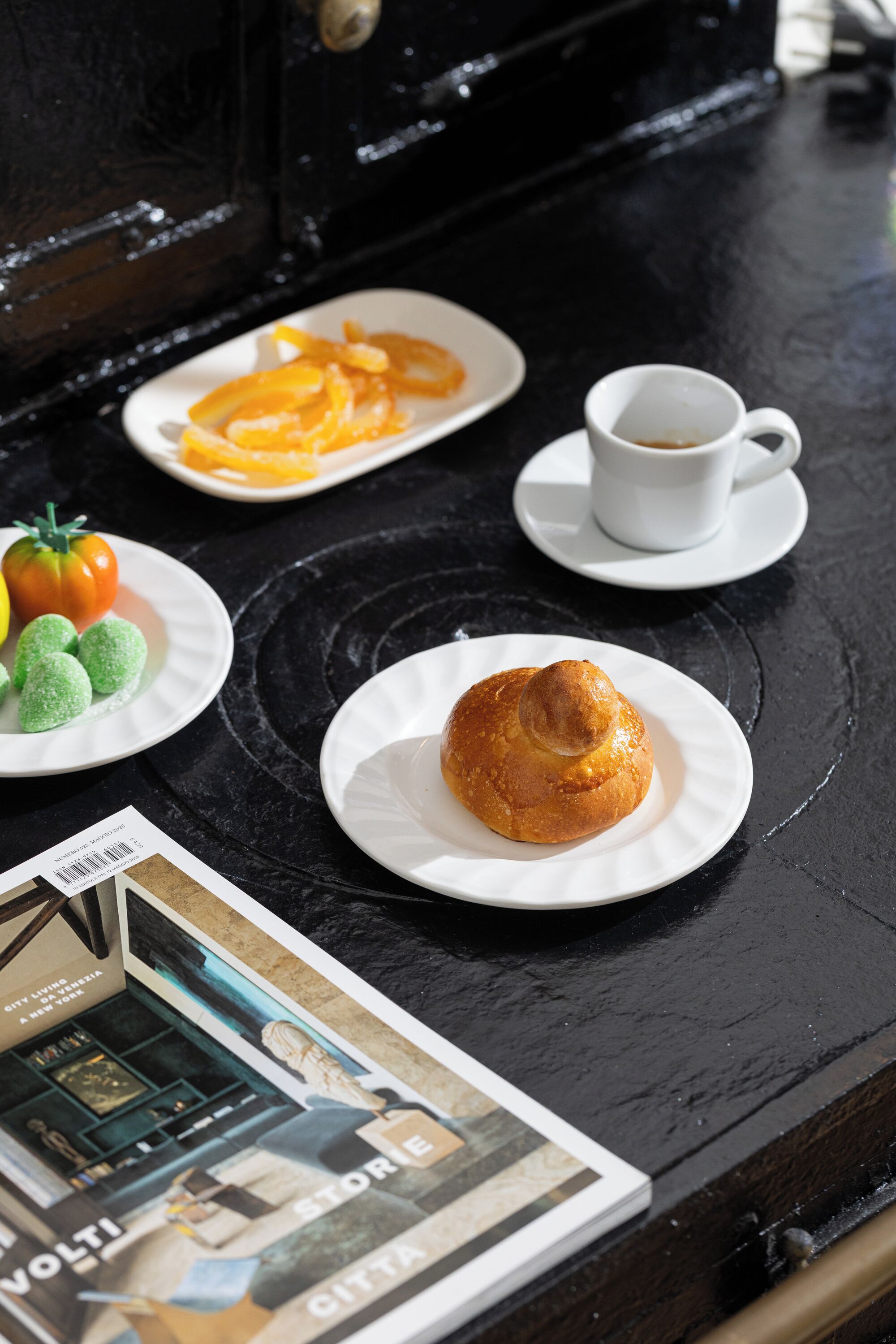 A table with a pastry, a cup of coffee, and plates with food items.