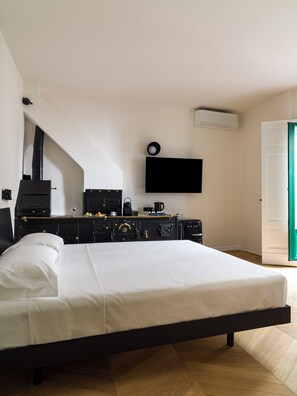 Una camera da letto con un letto, un comò nero, una televisione a schermo piatto e un pavimento in legno.