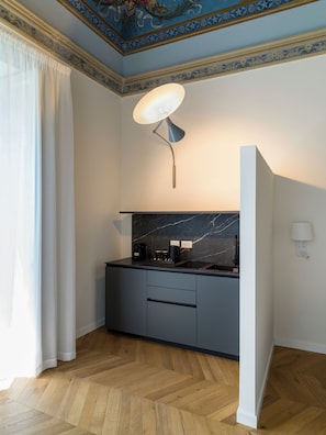 A modern kitchen with a marble countertop, a coffee machine, and a wall-mounted light fixture. - Palazzo settanta (Catania)