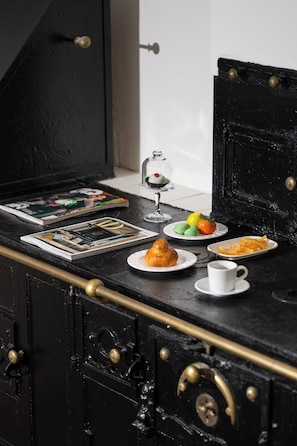 A black wooden table with a glass dome containing a dessert, a plate with pastries, a cup, and a magazine. - Palazzo settanta (Catania)