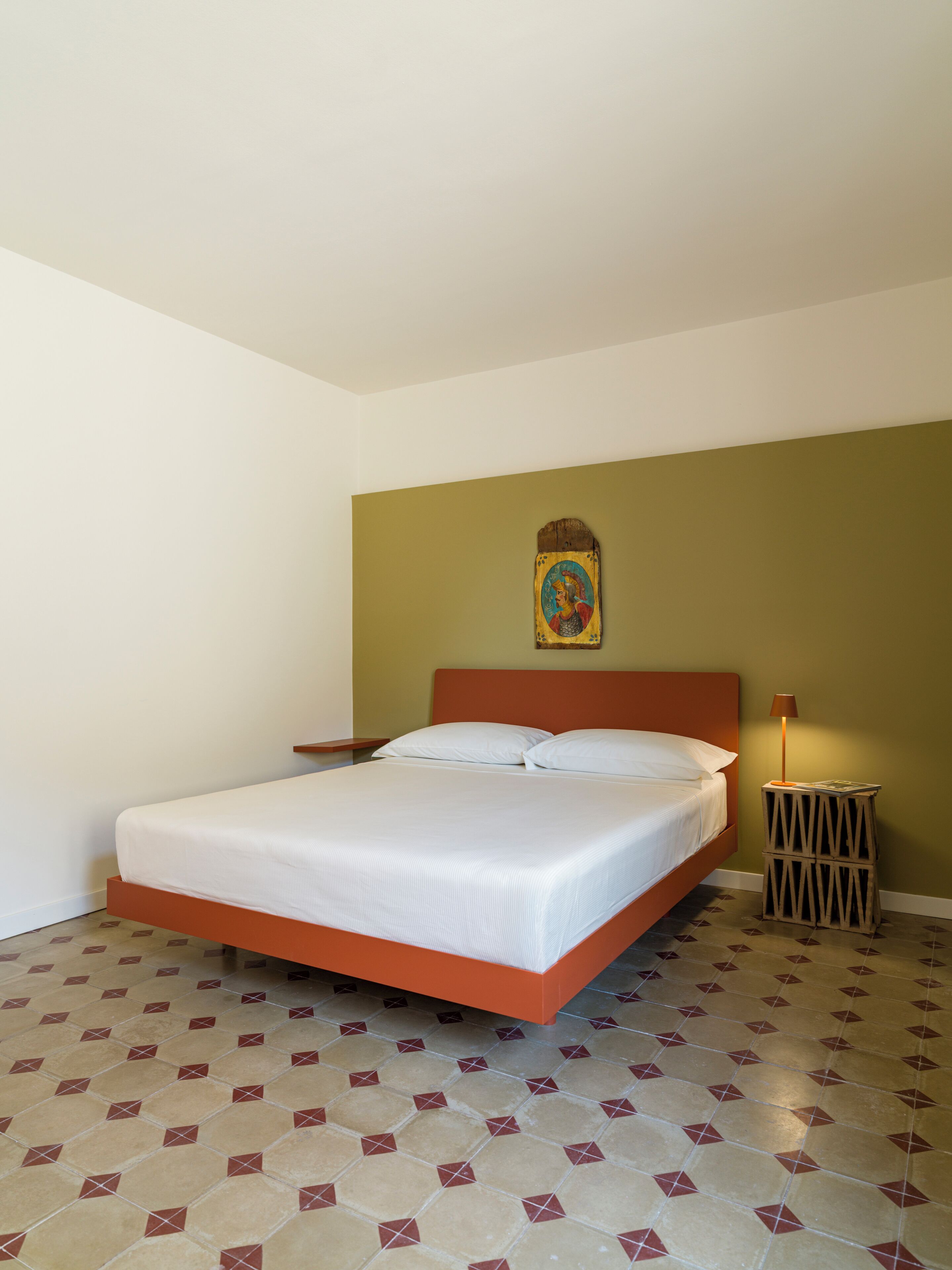 A single bed with a wooden headboard, a bedside table, and a wall-mounted lamp.
