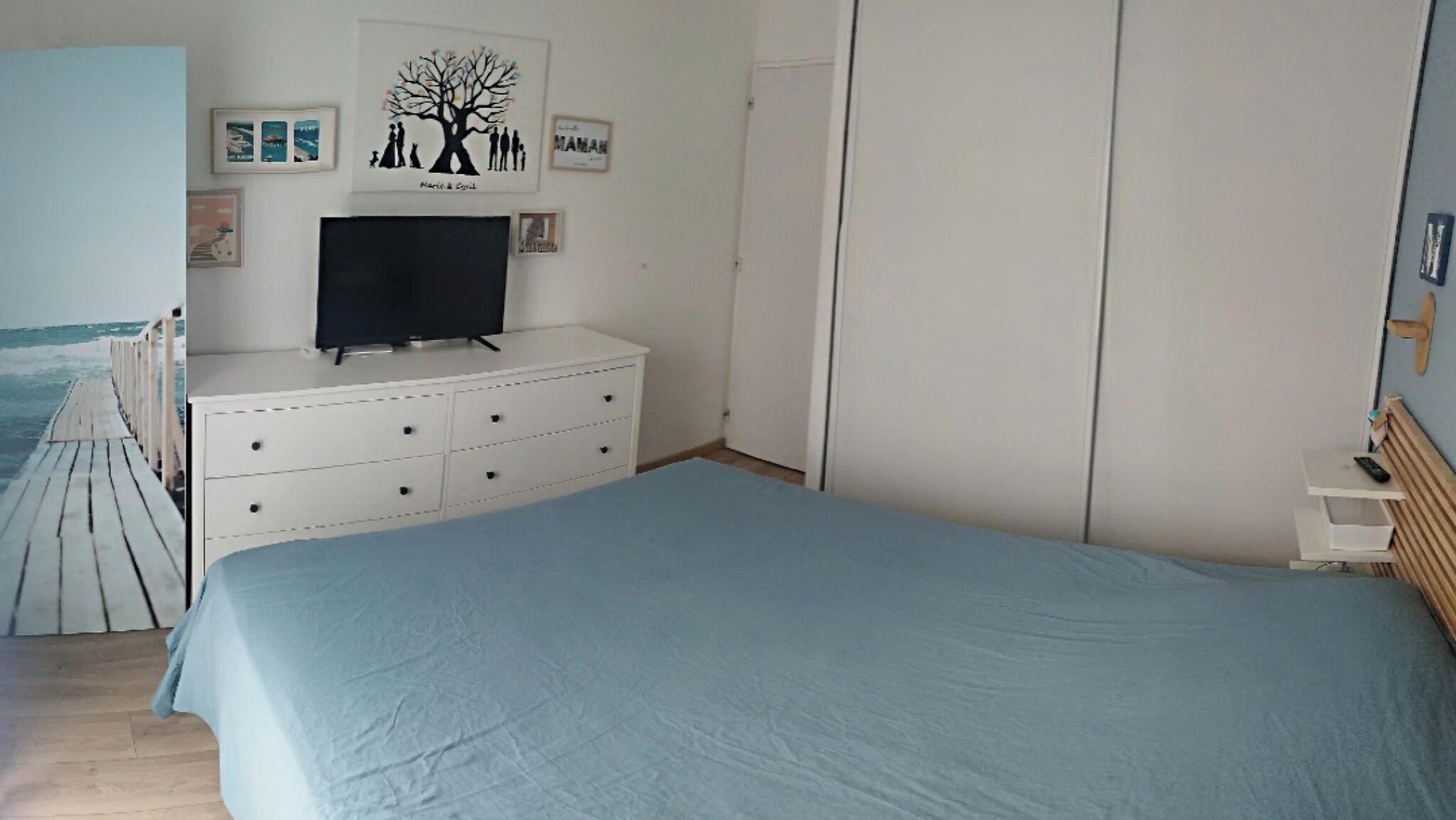 Une chambre à coucher comprenant un lit, une commode, un téléviseur et une armoire.