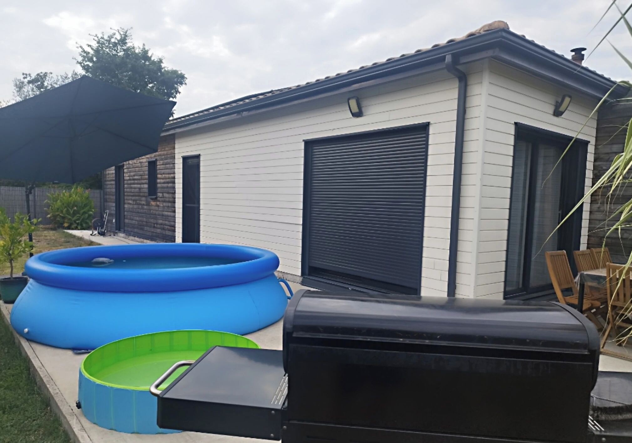 A residential outdoor area with a swimming pool, a barbecue grill, and a shed.