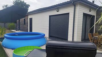 A residential outdoor area with a swimming pool, a barbecue grill, and a shed.