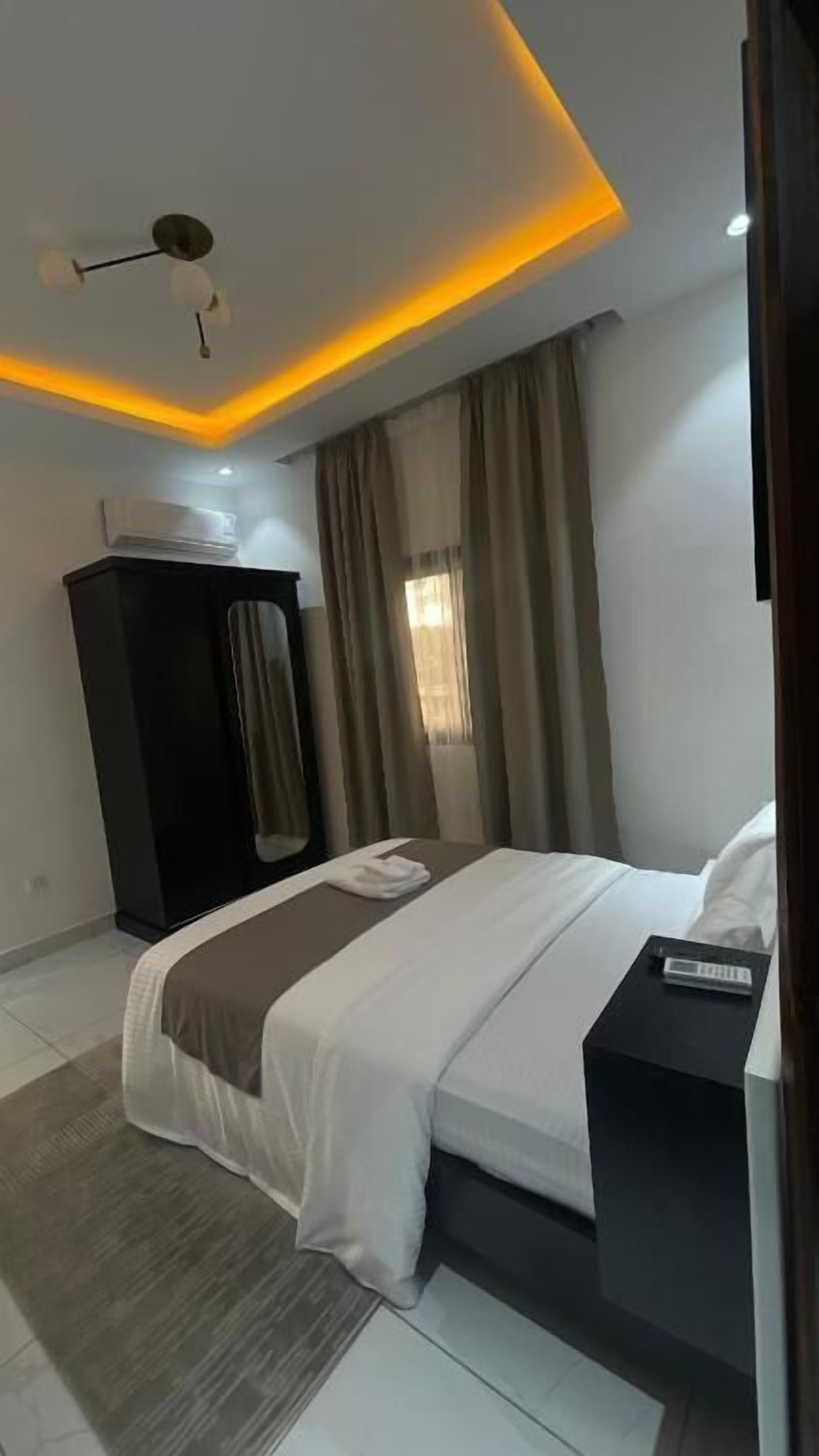 A modern bedroom with a bed, bedside table, and a ceiling light fixture.