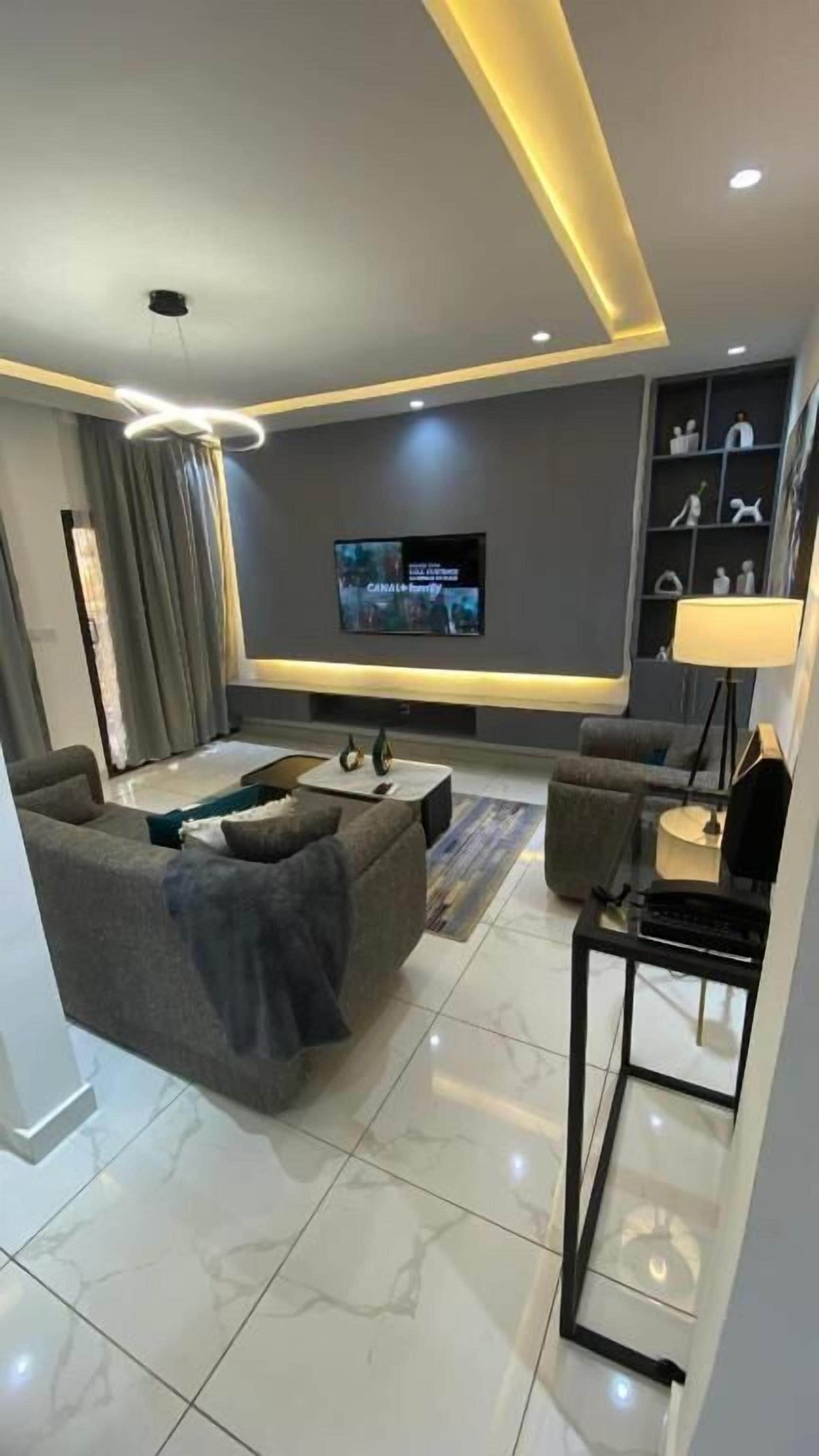 Una sala de estar moderna con un sofá, una mesa de centro, un televisor y estanterías.
