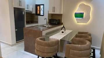 Een moderne keuken met witte kasten, een centraal eiland en een eethoek met twee stoelen.