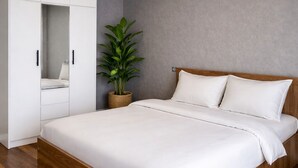 Un dormitorio con cama, armario, lámpara de techo y planta en maceta.