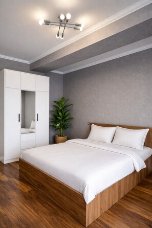 A bedroom with a bed, a wardrobe, a ceiling light fixture, and a potted plant. - Stylish 2BR Apt in Saburtalo | Bright & Cozy (T'bilisi)